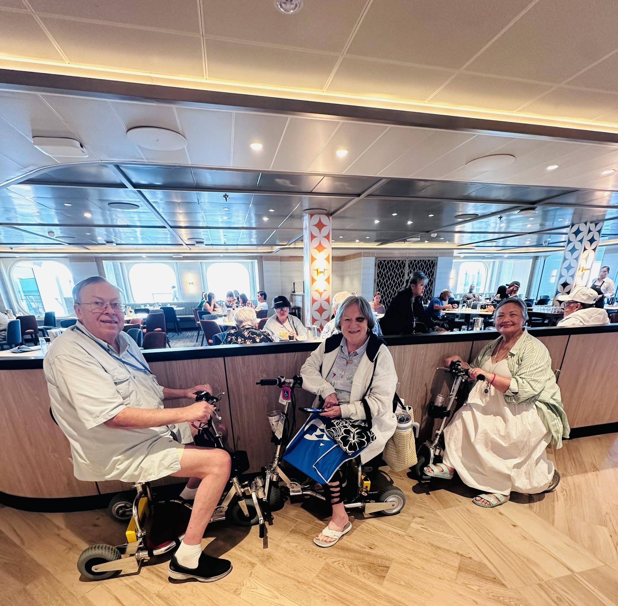 3 friends on the TravelScoot Escape mobility scooter on a cruise.