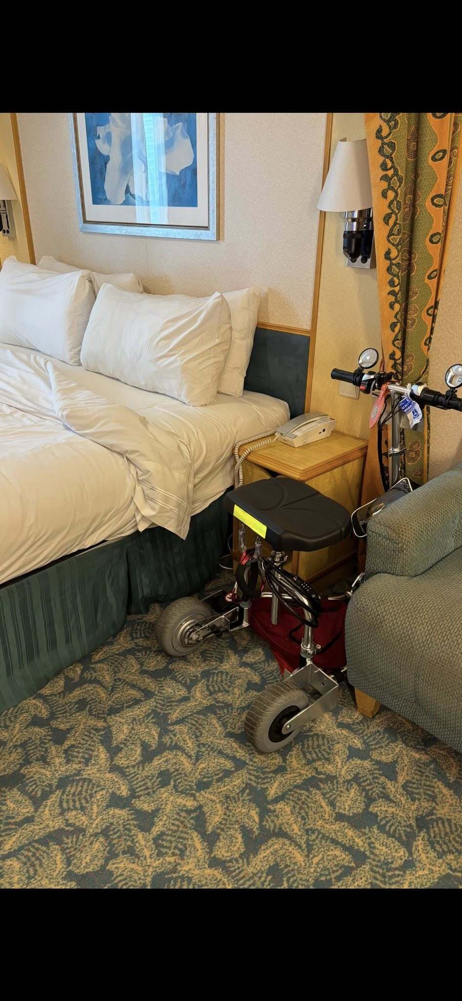 A mobility scooter is nestled between a bed and a night stand.