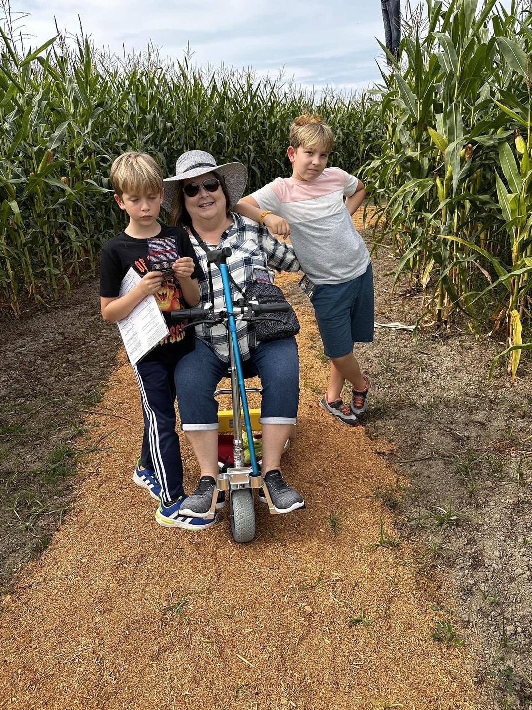 Person with kids on a mobility scooter in a corn field.