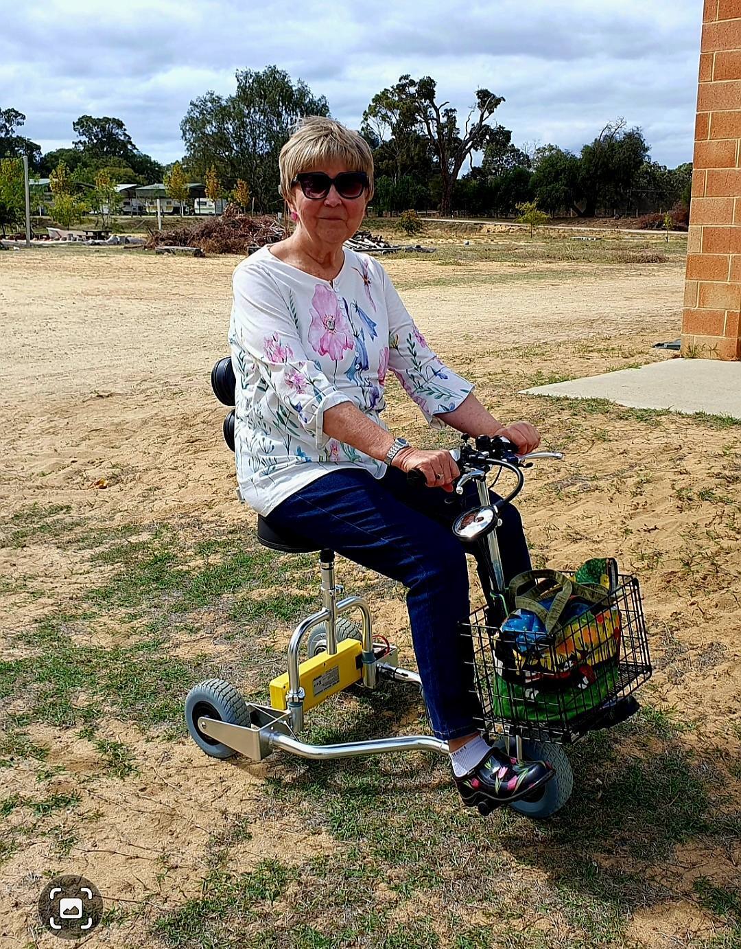 Woman on mobility scooter posing on a field of dry grass.