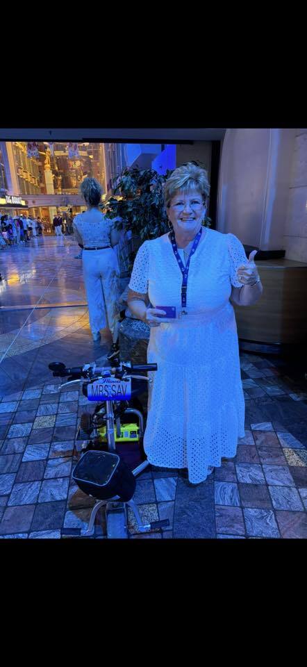 Woman standing next to her mobility scooter on a cruise at night.