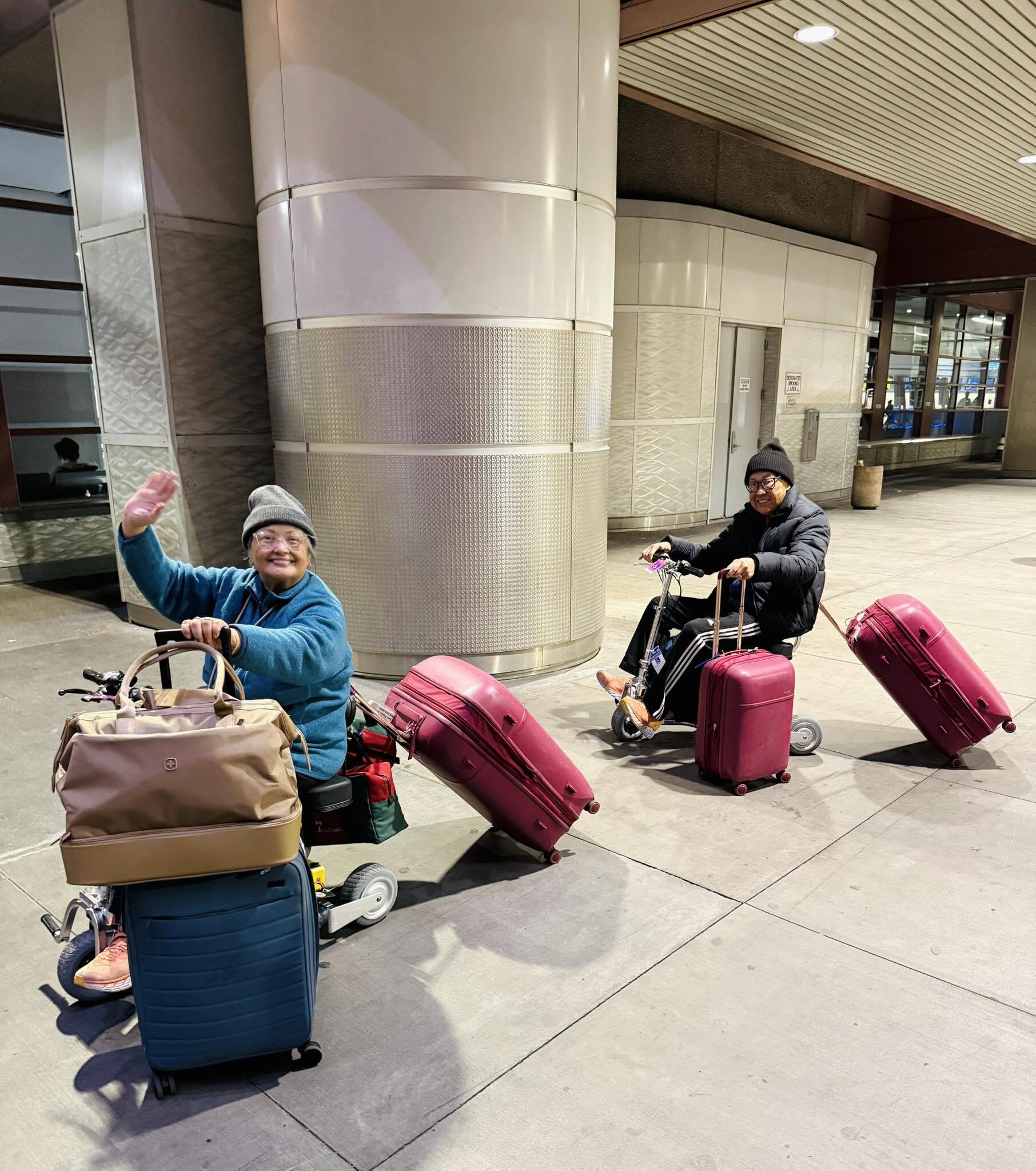 Man and woman towing luggage on his and hers mobility scooters.